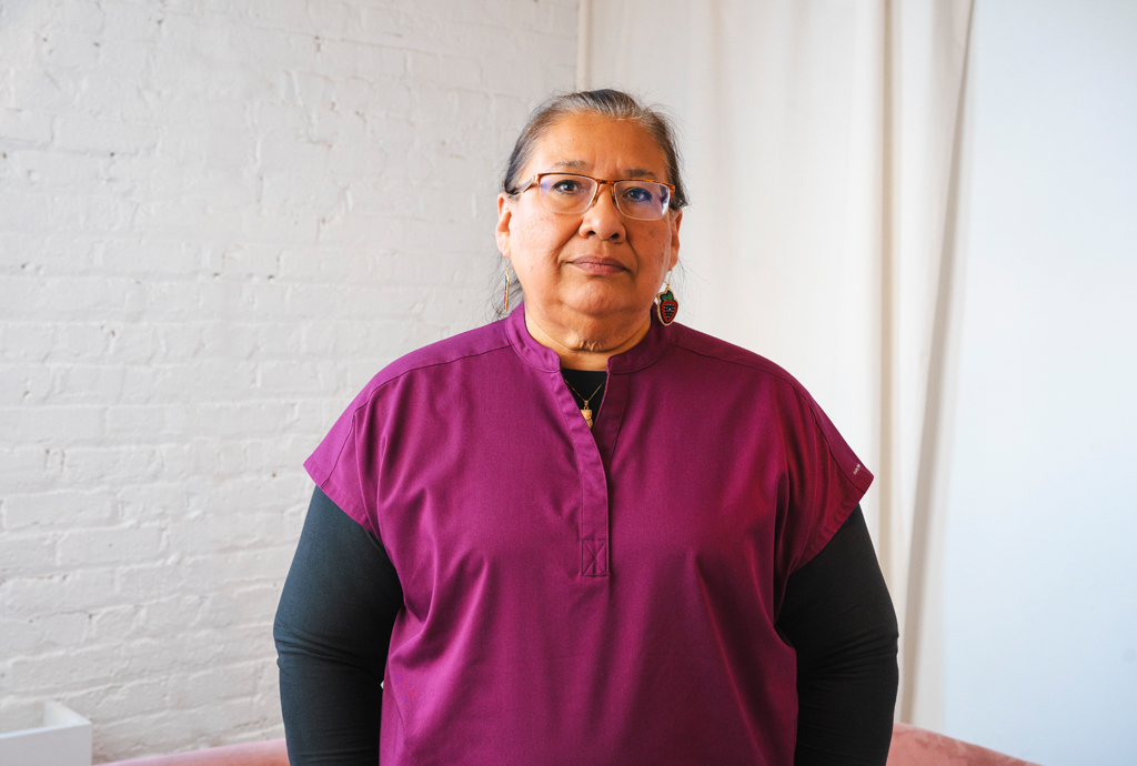 Indigenous woman in scrubs posing for the camera