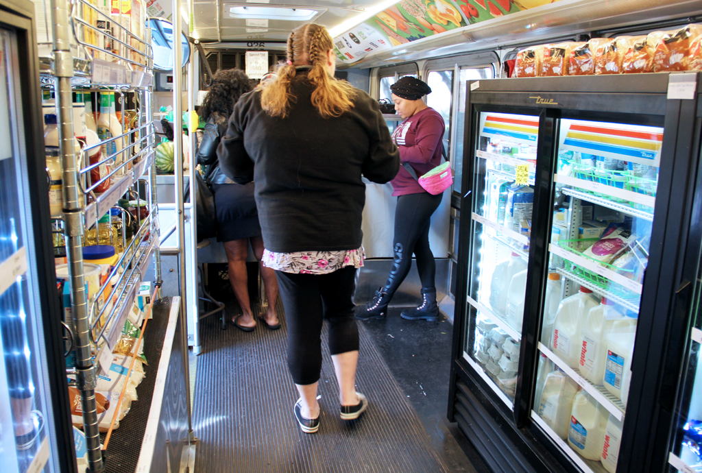 A woman waits in line to buy groceries on a Twin Cities Mobile Market bus