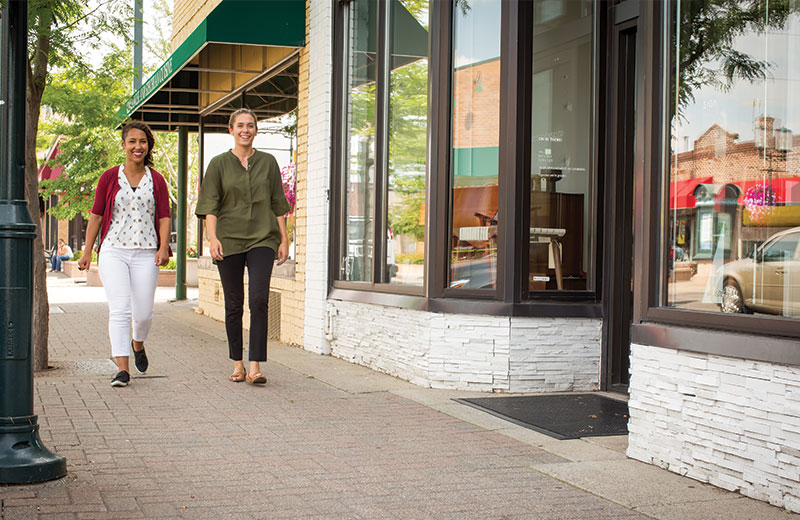two young women walking by storefronts