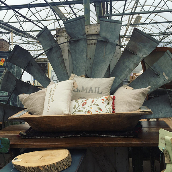 pillows in a wooden trough with a metal windmill blade in the background