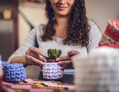 Woman wrapping cactus in homemade crochet pot