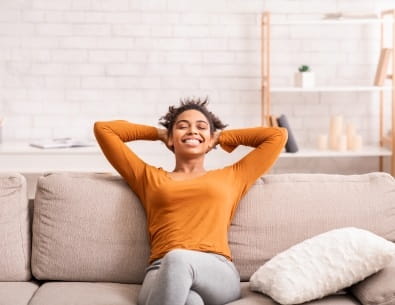 Person reclining on couch with hands behind head, generally happy and relaxed