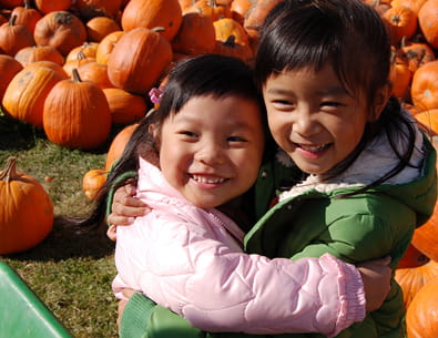 kids hugging outside a pumpkin patch