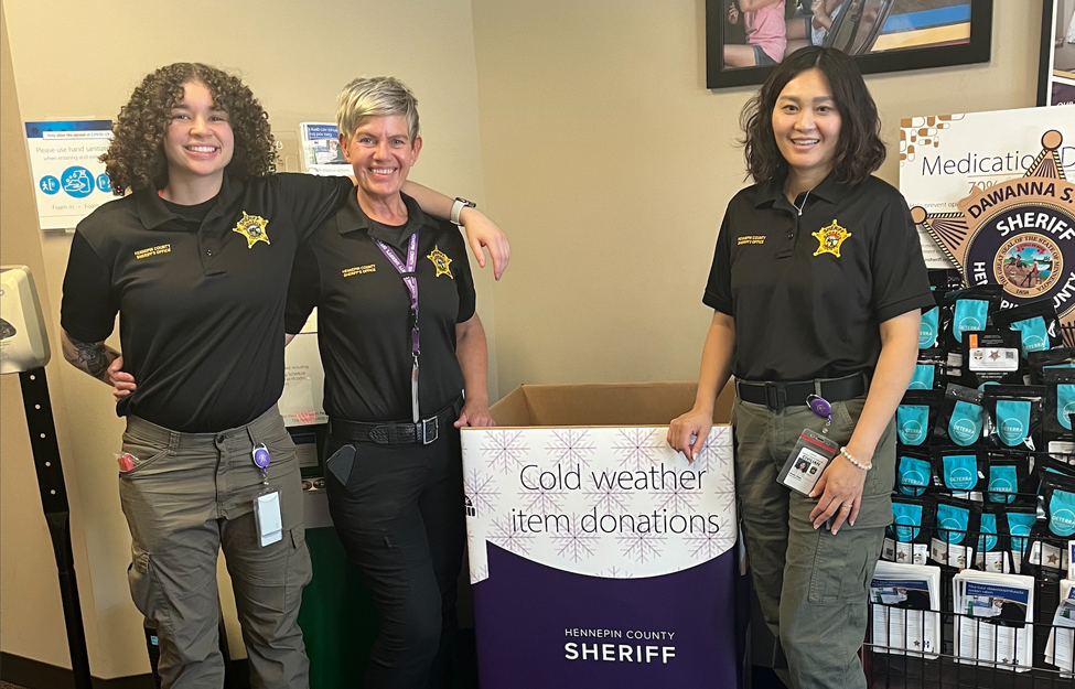 sheriff office staff standing next to donation box