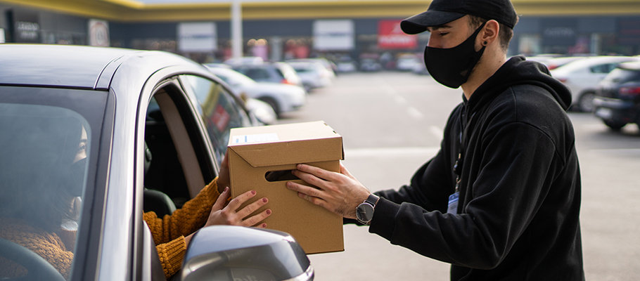 Man in mask handing box through a car window