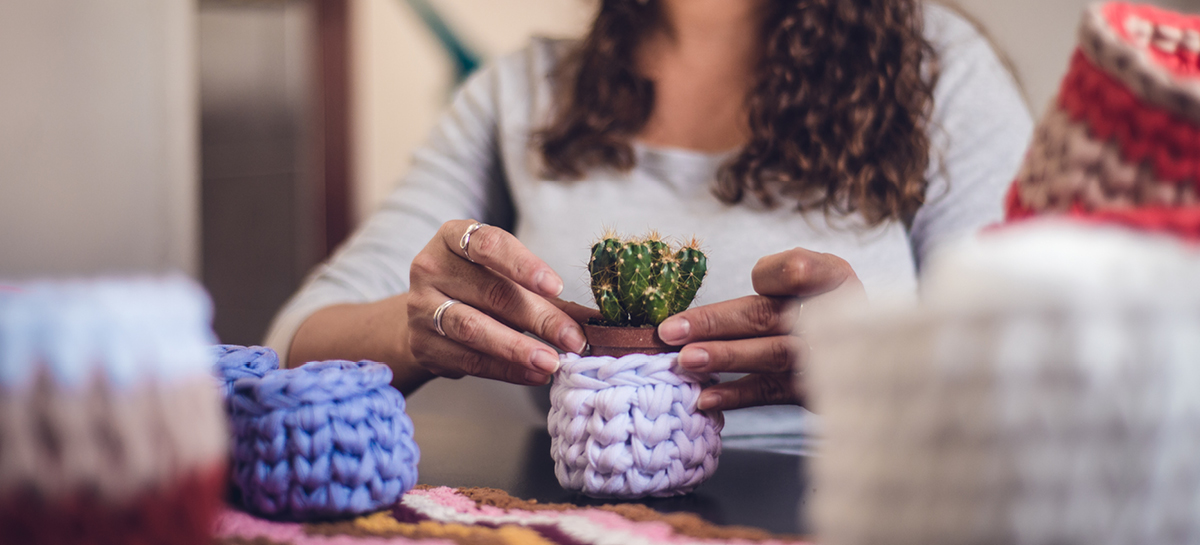 Woman wrapping cactus in homemade crochet pot