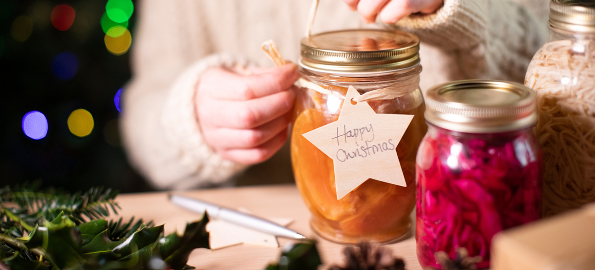 Close up of canned fruit in jar with twine wrap holding note that says, Happy Christmas