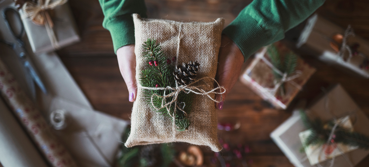Close up of hands holding present wrapped in burlap and twine