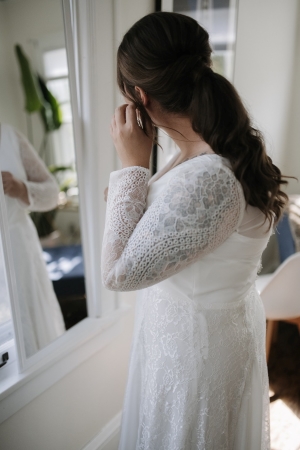 Bride putting on earrings in a mirror