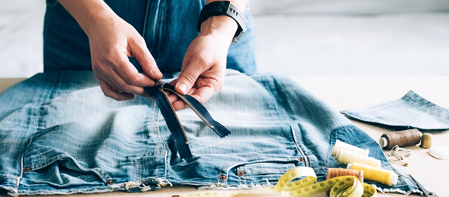 Person sewing a new zipper on jeans