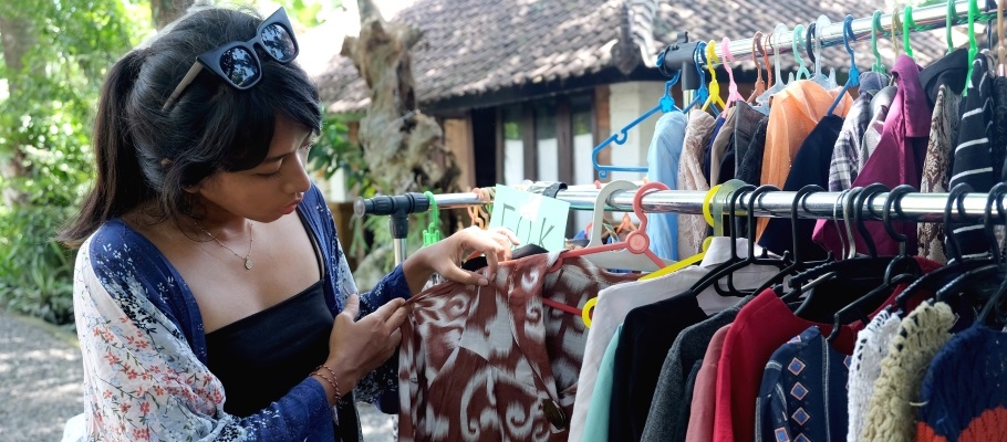 Woman looking through rack of clothing at a clothing swap