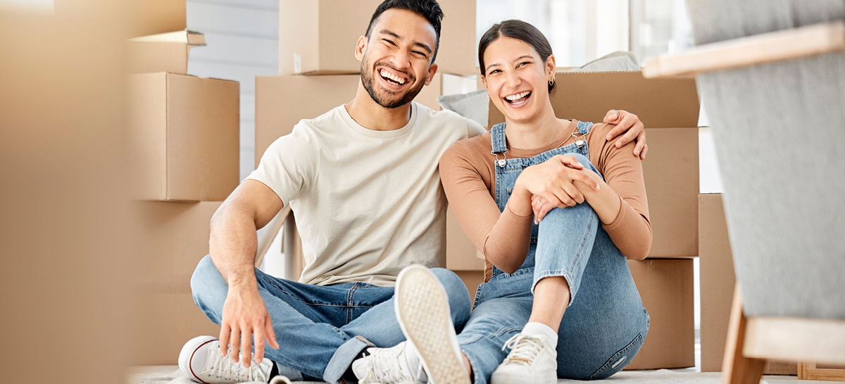 Young couple sitting in their new home surrounded by boxes to unpack