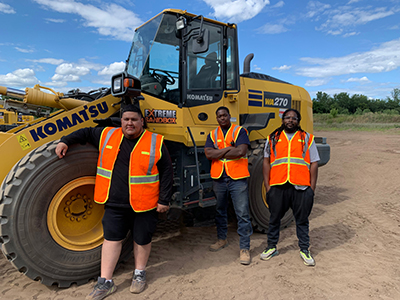 3 young men infront of heavy machinery