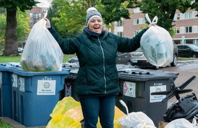 Woman triumphantly holding up two bags of litter during clean up event.