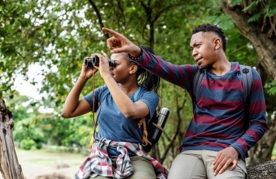 Man pointing while woman looks through binoculars