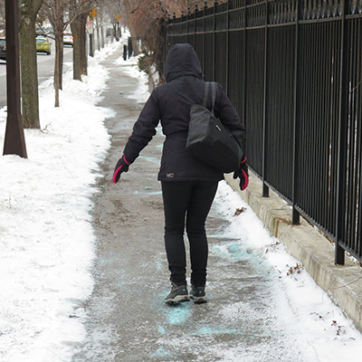 Woman walking on icy sidewalk covered in sidewalk salt