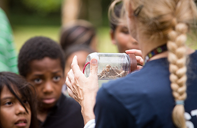 Youth looking at jar of materials while on outdoor field trip