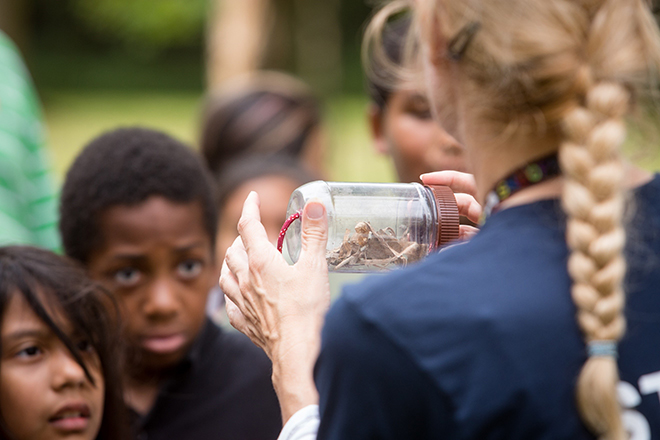 Youth looking at jar of materials while on outdoor field trip